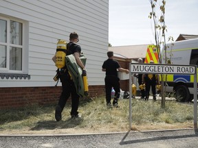 British firefighters carry equipment towards a property being searched on Muggleton Road in Amesbury, England, Friday, July 6, 2018. British police are scouring sections of Salisbury and Amesbury in southwest England, searching for a container feared to be contaminated with traces of the deadly nerve agent Novichok.