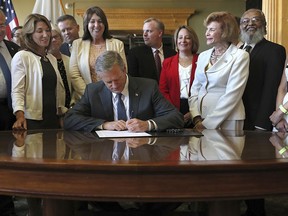 Massachusetts Gov. Charlie Baker signs legislation repealing the state's archaic anti-abortion laws, in Boston on Friday, July 27, 2018. Massachusetts on Friday became the first state since President Donald Trump nominated Brett Kavanaugh to the U.S. Supreme Court to abolish from its books an abortion ban that predates the 1973 Roe v. Wade ruling.