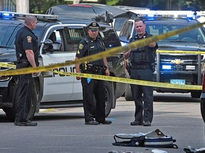 Officers work at the scene where a Weymouth police officer was shot and killed while in a foot chase with a suspect following a vehicle crash on Sunday, July 15, 2018, in Weymouth, Mass.