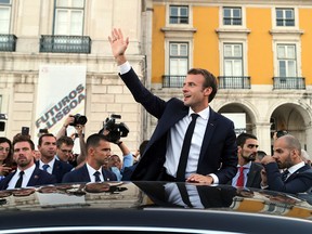 French President Emmanuel Macron waves to well-wishers outside the European Maritime Safety Agency headquarters in Lisbon on July 27, 2018.