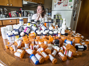 Mary Shuttleworth sits in her kitchen with bottles of medication that she has consumed in the past year to help with pain from a car accident six years ago.