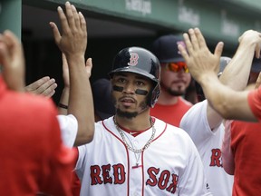 Boston Red Sox's Mookie Betts is welcomed to the dugout after scoring on an RBI-double by J.D. Martinez off a pitch by Minnesota Twins' Jose Berrios in the second inning of a baseball game, Sunday, July 29, 2018, in Boston.