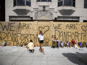 People write messages on a makeshift memorial remembering the victims of a shooting on Sunday evening on Danforth Avenue, in Toronto on Tuesday, July 24, 2018.