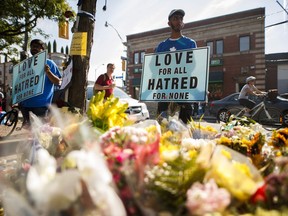 A man holds a sign reading "Love for All Hatred of None" at a memorial remembering the victims of a shooting on Sunday evening on Danforth, Avenue in Toronto on Tuesday, July 24, 2018.