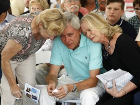 Carl Hiaasen, center, brother of Rob Hiaasen, one of the journalists killed in the shooting at The Capital Gazette newspaper offices, is consoled by his sister Judy, right, and Rob Hiaasen's widow, Maria, during a memorial service, Monday, July 2, 2018, in Owings Mills, Md.