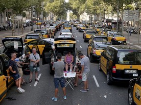 Taxi drivers block the Gran Via avenue in Barcelona, Spain, Monday, July 30, 2018. Taxi drivers in Barcelona are blocking traffic on a major thoroughfare as part of an indefinite strike to protest the use of ride-hailing apps like Uber and Cabify.