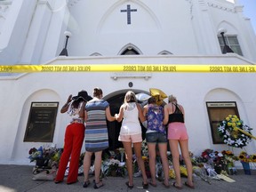 FILE - In this June 18, 2015, file photo, a group of women pray together at a makeshift memorial on the sidewalk in front of the Emanuel AME Church in Charleston, S.C. The historic South Carolina church where nine black worshippers were slain is unveiling the design for a memorial to the victims. Emanuel AME Church in Charleston will release the plans at an announcement Sunday, July 15, 2018, as part of its 200th anniversary celebration. The memorial was designed by Michael Arad, the architect behind the 9/11 Memorial in New York.