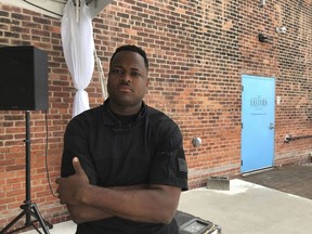 In this July 18, 2018 photo, Ibrahim Mission sits outside The Eastern, an Eastern Market event space where Detroit Mercantile Co. Owner Robert Stanzler spat in his face during a dispute Tuesday, July 17, in Detroit. Mission was providing security Tuesday at a social justice gathering when Stanzler grew disgruntled over some participants parking on his property.