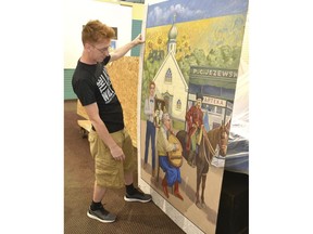 In this undated photo, Joe Kochut, Hamtramck Historical Museum vice chairperson, looks at a panel for the Ukrainian-American portion of a mural by artist Dennis Orlowski for the "Coming to Hamtramck" display at the museum in Hamtramck, Mich. The mural, a celebration of immigration and local history, is due to be unveiled officially July 19.