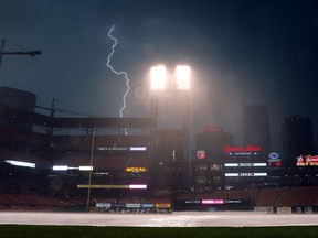 Lightning flashes in the distance as a thunderstorm passes over Busch Stadium during a rain delay in a baseball game between the St. Louis Cardinals and the Cincinnati Reds Saturday, July 14, 2018, in St. Louis. The rain delay was the second of the game.