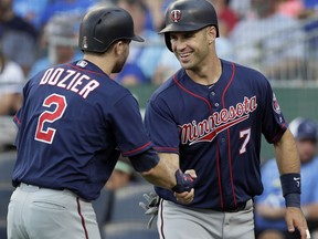 Minnesota Twins' Brian Dozier (2) congratulates teammate Joe Mauer (7) after Mauer scored on a single by Eddie Rosario during the first inning of a baseball game against the Kansas City Royals at Kauffman Stadium in Kansas City, Mo., Saturday, July 21, 2018.