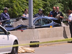 In this Monday, July 23, 2018 photo, emergency personnel work at the scene of an accident on Forest Park Parkway in St. Louis. Authorities say 58-year-old Janet Torrisi-Mokwa, a prominent businesswoman and wife of former St. Louis chief Joe Mokwa, was killed instantly when a 1-ton chunk of concrete fell from a bridge over a roadway and crushed her car.