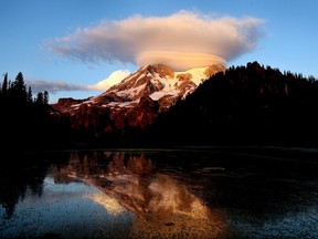 In this September 2012, file photo, a cloud hovers over Mount Rainier at sunset in a view from Klapatche Park Camp at Mount Rainier National Park, Wash.