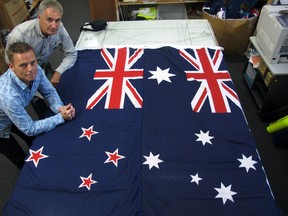 In this March 3, 2014, file photo, Victor Gizzi, left, and David Moginie, managers at flag manufacturer Flagmakers, pose next to flags of New Zealand, left, and Australia, in their factory near Wellington, New Zealand.