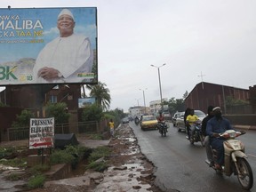 In this Wednesday, July 18, 2018 photo, motorbike taxis ride past a giant billboard of Malian Incumbent President, Ibrahim Boubacar Keita that reads "the great Mali advance"  in Bamako, Mali.  As deadly attacks by extremists become more brazen in Mali, officials and citizens fear this month's presidential election will be at risk from growing insecurity.