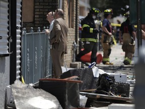 Investigators stand outside of a house where two children were killed in a morning fire, Friday, July 13, 2018, in Union City, N.J.  The fire at the multifamily home started shortly before 9 a.m. Friday. It quickly consumed the home, sending flames and smoke shooting high into the sky. It was brought under control about 30 minutes later.