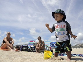 Logan Eng, 2, right, plays with sand as his mom, Avia Eng, center, of Howell, N.J., and their friend Jenny Caruso, left, of Red Bank, N.J., look on during a beach outing, Friday, July 20, 2018, in Long Branch, N.J. Avia Eng said she's in favor of a bill signed by New Jersey Gov. Phil Murphy banning smoking on beaches and parks because she doesn't want her child exposed to the smoke and trash left behind by smokers. Fines would start at $250 for a first offense and go up to $1,000 for a third offense for people smoking out of designated areas.