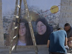 Palestinians hang a poster showing Nariman Tamimi, right and her daughter Ahed, during preparations for their upcoming release from an Israeli prison after serving an eight month sentence, at the family house in the West Bank village of Nebi Saleh, west of Ramallah, Saturday, July 28, 2018.