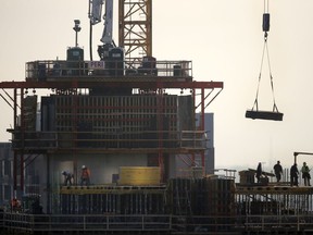 FILE - In this Jan. 18, 2017 file photo, construction personnel work on a building project just south of Chicago's Loop. The U.S. economy surged in the April-June quarter, growing at an annual rate of 4.1 percent. That's the fastest pace since 2014, driven by consumers who began spending their tax cuts and exporters who sought to get their products delivered ahead of retaliatory tariffs.