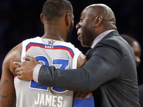 FILE - In this Feb. 19, 2017, file photo, former NBA player Magic Johnson reacts as he talks with Eastern Conference's LeBron James, of the Cleveland Cavaliers, during the first half of the NBA All-Star basketball game in New Orleans. James, the game's biggest star, will now lead a young Lakers team run by Lakers Hall of Famer Magic Johnson.