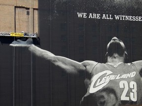 FILE - In this July 10, 2010, file photo, workmen remove a large mural of NBA basketball star LeBron James from a building in downtown Cleveland. For the second time in his career, James is saying goodbye to the Cleveland Cavaliers. The four-time NBA MVP announced Sunday night, July 1, 2018, that he has agreed to a four-year, $154 million contract with the Los Angeles Lakers.