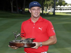 FILE - In this July 16, 2017, file photo, Bryson DeChambeau celebrates with the trophy after winning the John Deere Classic golf tournament, at TPC Deere Run in Silvis, Ill. DeChambeau will defend a title for the first time in his career this week at the John Deere Classic.