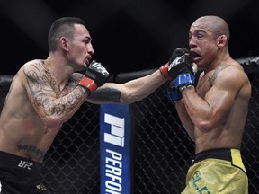 FILE - In this Dec. 3, 2017, file photo, Max Holloway, left, punches Jose Aldo, of Brazil, during the third round of a UFC 218 featherweight mixed martial arts bout in Detroit. UFC featherweight champion Holloway's representatives say he is dropping out of his title defense against Brian Ortega at UFC 226 this weekend due to apparent concussion symptoms. Holloway's management team announced the decision in a statement issued Wednesday night, July 4, 2018, three days before the bout.