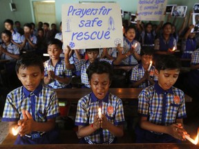 FILE - In this July 9, 2018, file photo, students at a school in Ahmadabad, India, hold candles and pray for a group of Thai youth soccer players and their coach who have been trapped since June 23, in Mae Sai, Chiang Rai province, northern Thailand. For the boys and their coach, we have only a hint of what it might have been like. But for the rest of us, watching from afar as the world's journalists beamed us live shots and the unknowable became known drip by captivating drip, we knew only one thing: It was hard to look away.