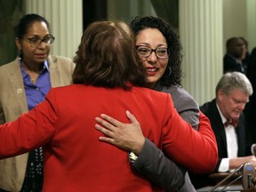 FILE - In this May 25, 2018 file photo, Assemblywoman Cristina Garcia, D-Bell Gardens, right, is hugged by Assemblywoman Eloise Gomez Reyes, D-Grand Terrace, on her first day back at the Assembly in Sacramento, Calif., since an investigation into sexual misconduct charges. Garcia took a three-month leave of absence after a groping allegation and other claims of inappropriate behavior surfaced. Outside investigators cleared her of the groping claim but found she used vulgar language in violation of the Assembly's sexual harassment policy.