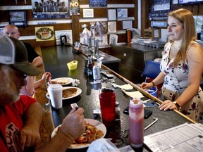 Kendra Snyder, right, talks with patrons at Checkers Bar & Grill in Mount Union, Pa., on Monday, July 16, 2018. At age 12, Snyder passed out from a condition where her heart was missing over 1,000 beats every day. She had heart surgery for it when she turned 20, and doctors said the problem seemed to be fixed. Her cardiologist wanted to know whether her condition was inherited or not, so genetic tests where done. In March, Kendra was told her testing was inconclusive. She realized she shouldn't stress over it, because doing so would reduce her quality of life.