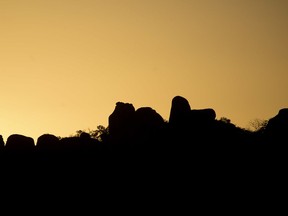 In this Tuesday, July 24, 2018 photo, the sun sets over the Matobo hills where, over 30 years ago, Zimbabwe army's Operation Gukurahundi ran from 1983 through 1987, when the Fifth Brigade rampaged through the southwestern provinces of Matabeleland. Residents of villages were rounded up and forced to attend all-night rallies for Zimbabwe's ruling party, ZANU-PF. Community leaders were beaten and sometimes killed in front of the gatherings.