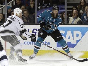 FILE - In this Dec. 23, 2017, file photo, San Jose Sharks center Joe Thornton, right, passes as Los Angeles Kings defenseman Alec Martinez (27) closes in during the first period of an NHL hockey game in San Jose, Calif. The Sharks have re-signed Thornton to a one-year contract. The team announced the deal on Thornton's 39th birthday Monday, July 2, 2018.