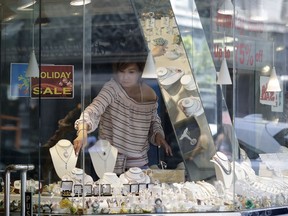 In this July 3, 2018, photo, a merchant arranges a display inside a jewelry store in San Francisco. On Monday, July 16, the Commerce Department releases U.S. retail sales data for June.