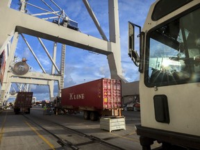 In this Thursday, July, 5, 2018 photo, Jockey trucks line up to under massive post-Panamax cranes to unload their 40-foot shipping container at the Port of Savannah in Savannah, Ga. The United States and China launched what Beijing called the "biggest trade war in economic history" Friday, July 6, imposing tariffs on billions of dollars of each other's goods amid a spiraling dispute over technology.