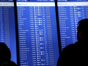 FILE - In this Jan. 4, 2018, file photo, people look at a display that shows mostly cancelled flights at Newark Liberty International Airport in Newark, N.J. If a trip is interrupted by unforeseen emergencies like weather, travel insurance may cover your losses as well as expenses incurred because of the disruption, like rebooking fees for flights or a hotel because you are stranded.