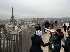 FILE - In this March 21, 2017, file photo, tourists watch Paris from the top of the Arc de Triomphe in Paris, France. The Eiffel Tower is seen background. The American Society of Travel Agents is starting to refer to agents as 'travel advisers' to better describe their emerging roles as trip planners rather than just booking agents. ASTA says they can add value to trips by finding freebies, perks and upgrades along with offbeat and authentic itineraries.