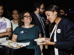 In this June 27, 2018 photo provided by Ocasio2018, Alexandria Ocasio-Cortez, right, 28, celebrates her Democratic congressional primary victory over 10-term incumbent Joe Crowley with campaign manager Virginia Ramos Rios, center left, and campaign staffer Daniel Bonthius, fourth from left, during an election night party at a pool hall in the Bronx borough of New York. Ramos Rios and Bonthius were part of a eclectic team that came together to help their candidate defeat an incumbent who spent  $3.4 million on his campaign.