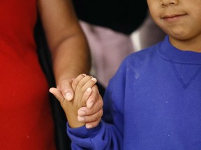 FILE - In this Friday, June 22, 2018, file photo, a mother, left, and son, from Guatemala, hold hands during a news conference following their reunion in Linthicum, Md., after being reunited following their separation at the U.S. border. On Monday, July 9, 2018, a California federal judge rejected the Trump administration's efforts to detain immigrant families in long-term facilities, calling it a "cynical attempt" to undo a longstanding court settlement.