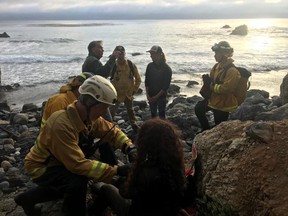 In this Friday, July 13, 2018, photo posted on the Monterey County, Calif., Sheriff's Office Twitter feed, authorities tend to Angela Hernandez, foreground center, after she was rescued, in Morro Bay, Calif. Authorities say a couple on a camping trip came upon Hernandez, from Oregon, who had been missing since July 6, after her car went over a cliff in coastal California. (Monterey County Sheriff's Office via AP)
