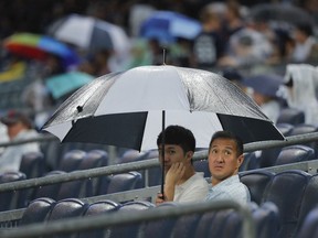 Baseball fans wait out a rain delay before a baseball game between the New York Yankees and the Kansas City Royals, Friday, July 27, 2018, in New York.