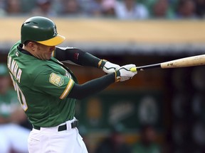 Oakland Athletics' Mark Canha swings for an RBI-single off San Francisco Giants' Dereck Rodriguez in the second inning of a baseball game Friday, July 20, 2018, in Oakland, Calif.