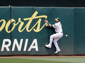 Oakland Athletics' Dustin Fowler crashes into the wall as he tries to catch a line drive double by Cleveland Indians' Francisco Lindor during the third inning of a baseball game Sunday, July 1, 2018, in Oakland, Calif.