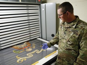 In this July 17, 2018, photo, Sgt. 1st Class Josh Mann, the Ohio Army National Guard historian, looks at a Civil War battle flag from the 148th Infantry Regiment inside the Beightler Armory in Columbus, Ohio. The Ohio National Guard is celebrating its 230 years of service.