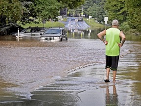 Louis Binino, of Mount Joy, Pa., looks at his SUV, far left, that became stranded in high water along Rt 772 in Mount Joy, Pa., Wednesday, July 25, 2018. Binino waded though the water to safety after climbing out the window of the vehicle. Days of drenching rains are closing roads, sending creeks and streams over their banks and causing businesses and to shut down in central Pennsylvania.