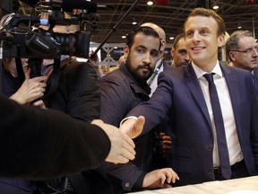 FILE - In this March 1, 2017 file picture centrist presidential candidate Emmanuel Macron, center, flanked by his bodyguard, Alexandre Benalla, left, visits the Agriculture Fair in Paris, Wednesday, March 1, 2017. Benalla an aide to President Emmanuel Macron, charged with security, has been seen in a video wearing a police helmet and beating up a student protester in May, reigning criticism on Macron notably due to the light punishment _ a two-week suspension.