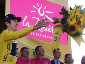 Stage winner Britain's Geraint Thomas and new overall leader throws his flowers to fans on the podium after the eleventh stage of the Tour de France cycling race over 108.5 kilometers (67.4 miles) with start in Albertville and finish in La Rosiere Espace San Bernardo, France.