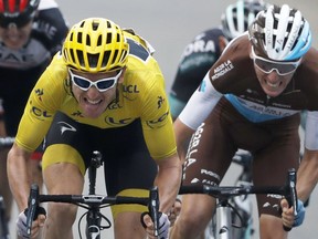 Britain's Geraint Thomas, wearing the overall leader's yellow jersey, grimaces as he sprints with France's Romain Bardet, right, and Ireland's Daniel Martin, left, towards the finish line of the nineteenth stage of the Tour de France cycling race over 200.5 kilometers (124.6 miles) with start in Lourdes and finish in Laruns, France, Friday July 27, 2018.