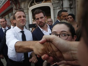 French President Emmanuel Macron greets people after visiting La Patisserie Bordelaise, a pastry shop in Bagneres de Bigorre, France, after the seventeenth stage of the Tour de France cycling race, Wednesday July 25, 2018.