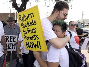 FILE - In this June 25, 2018, file photo, Diana Jung Kim, right, and Homer Carroll, both from Houston, hug during a protest outside the U.S. Border Patrol Central Processing Center in McAllen, Texas. More than 50 immigrant children under age 5 will be reunited with their parents by Tuesday's court-ordered deadline for action by Trump administration and the families will then be released into the U.S., a government attorney said Monday, July 9, 2018.