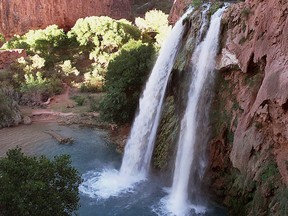 FILE - This 1997 file photo shows one of five waterfalls on Havasu Creek as its waters tumble 210 feet on the Havasupai Tribe's reservation in a southeastern branch of the Grand Canyon near Supai, Ariz. About 200 tourists are being evacuated from a campground on tribal land near famous waterfalls deep in a gorge off the Grand Canyon. Officials with the Havasupai Tribe say their reservation was hit with two rounds of flooding Wednesday, July 11, 2018, and early Thursday.